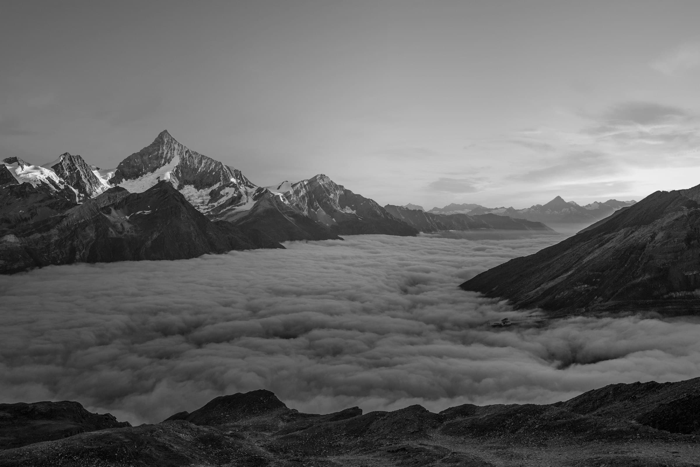 A mountain ridge rising over a sea of clouds, fine-art black and white photograph