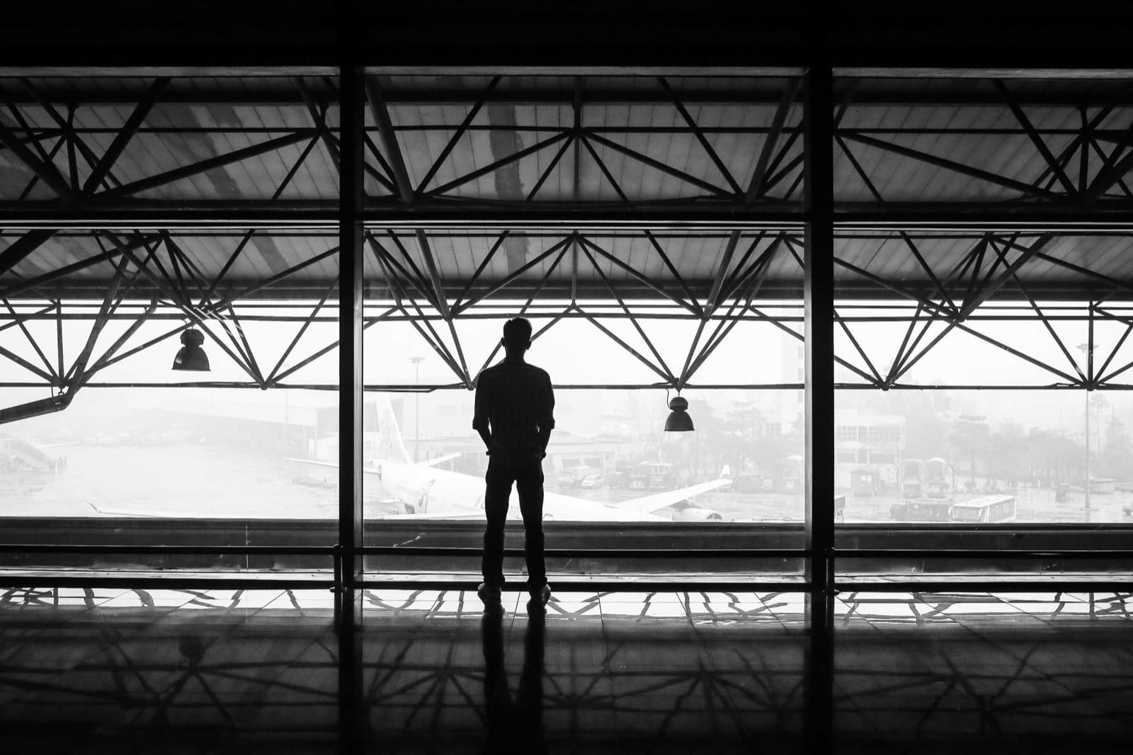 A silhouette standing in a steel-framed window, fine-art black and white photograph