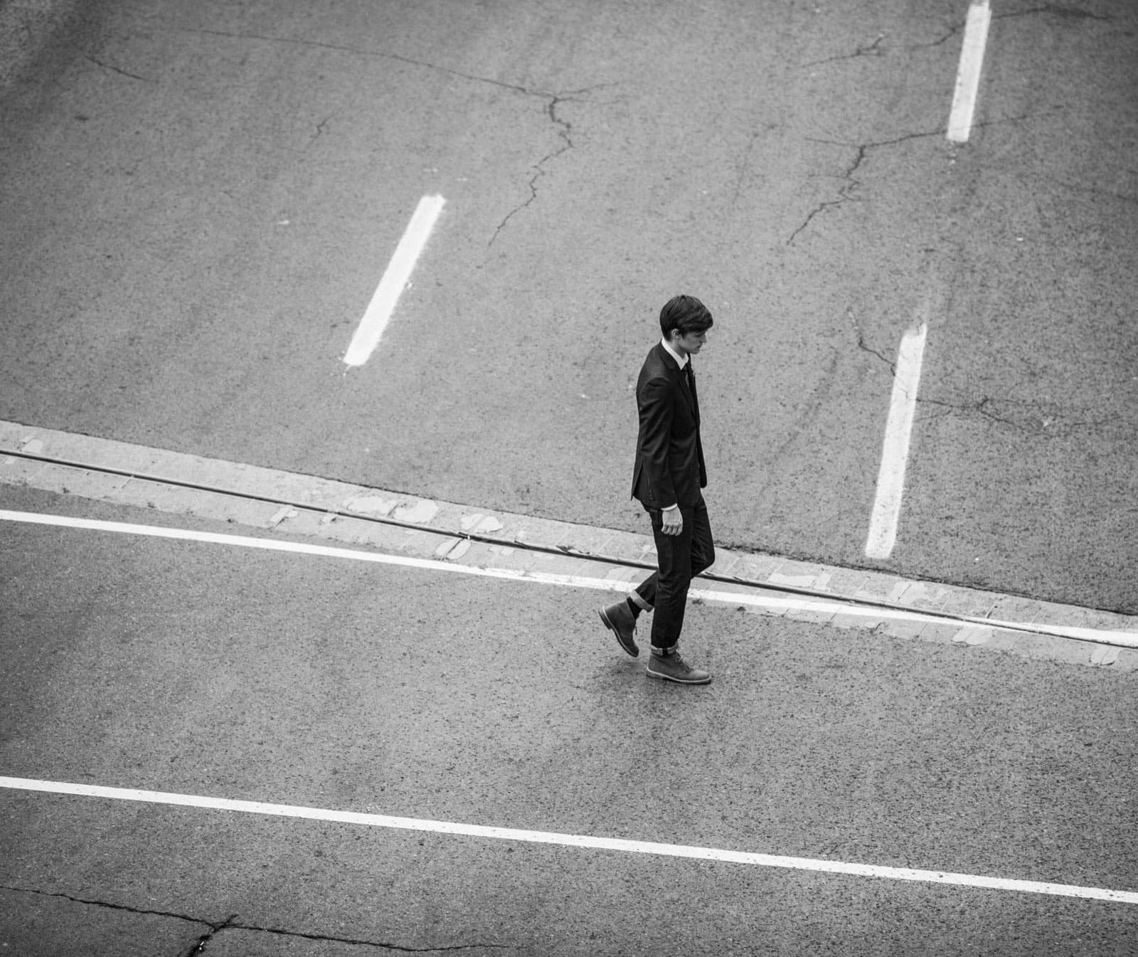 A lone figure crossing an empty road, fine-art black and white photograph