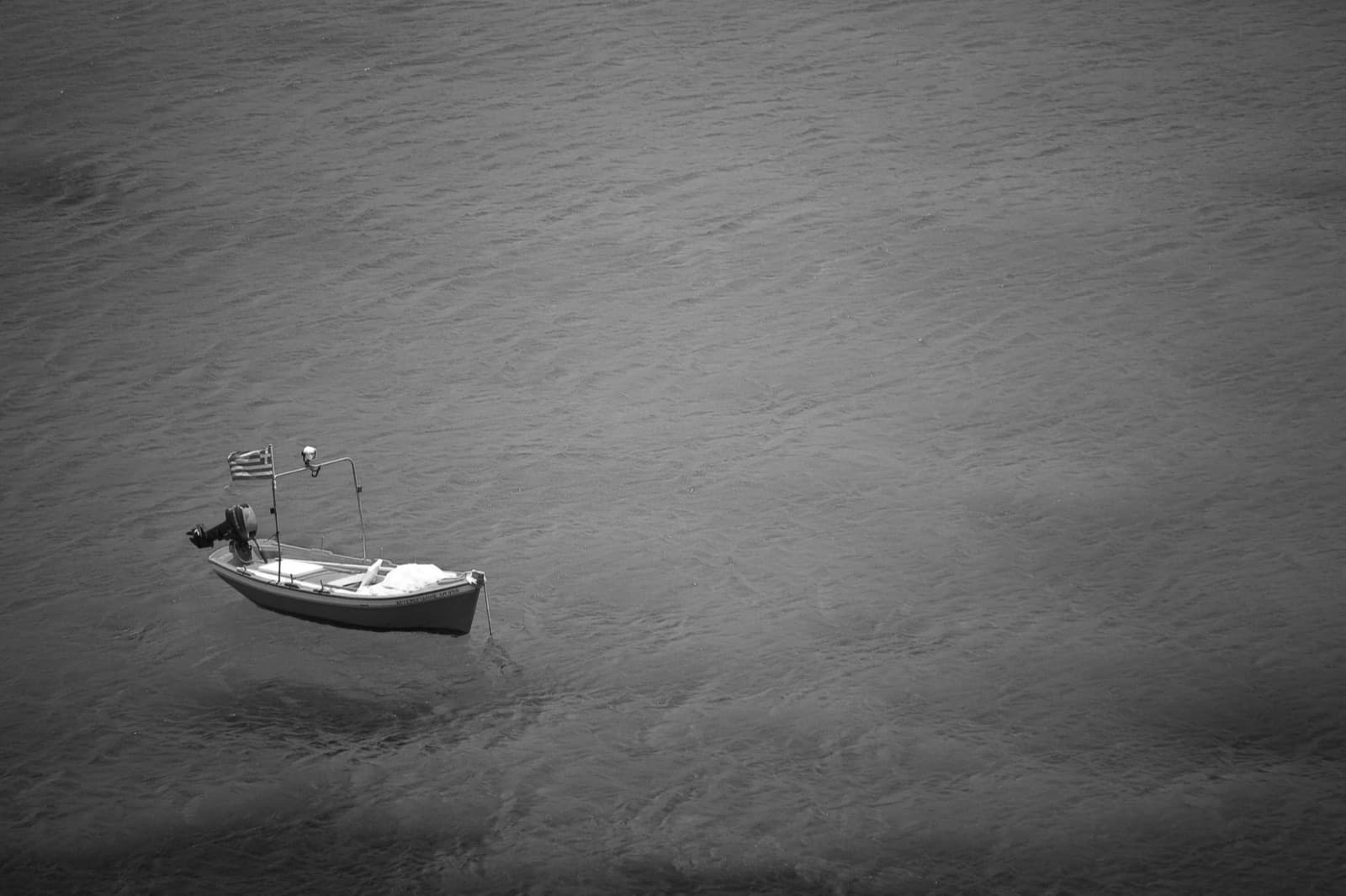 A small boat alone on open water, fine-art black and white photograph