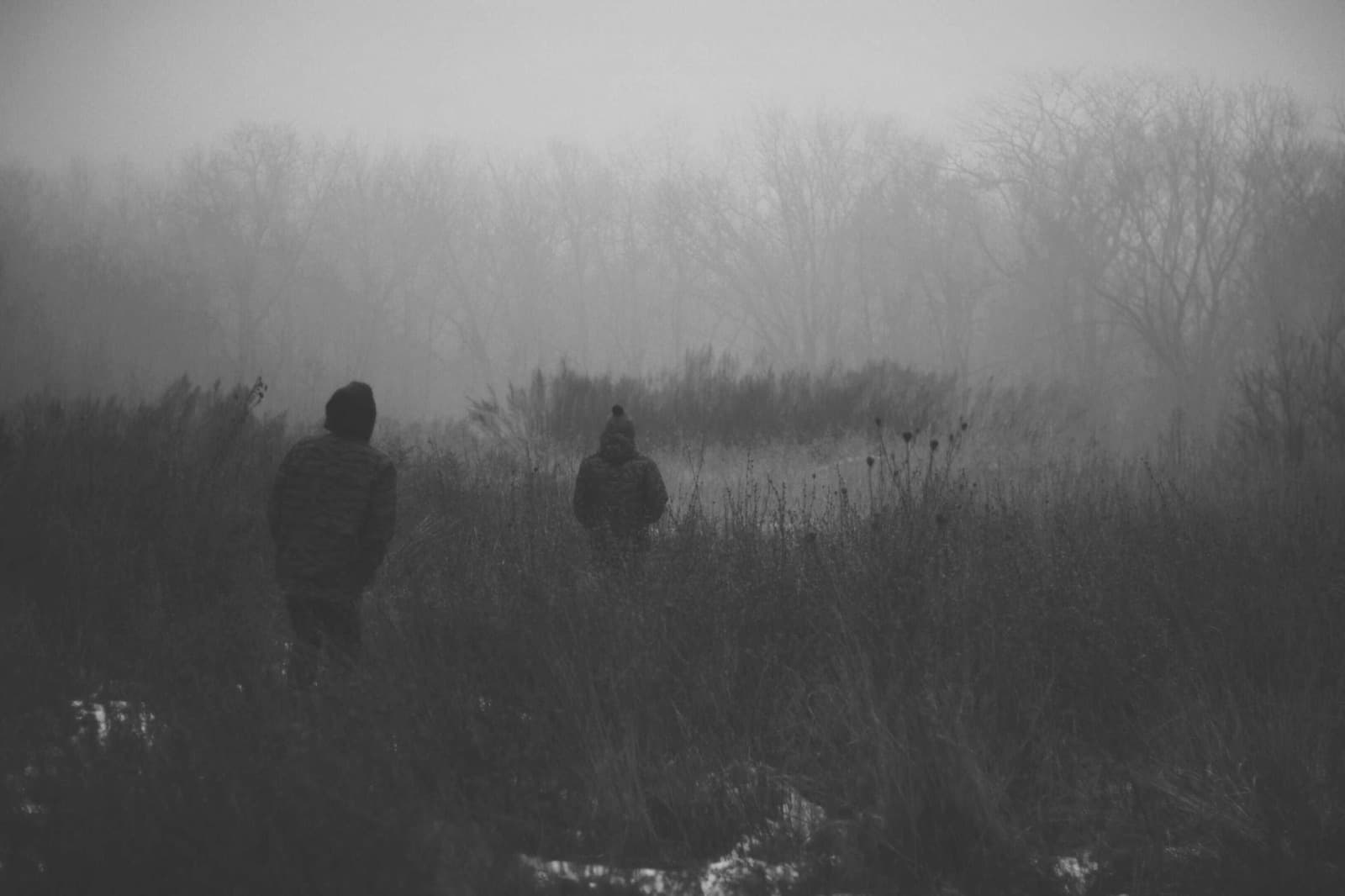 Two figures fading into a mist-covered field, fine-art black and white photograph